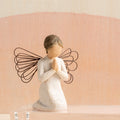 Willow Tree Angel of Prayer, 4"h hand-painted resin kneeling figure in cream dress, wire wings and hands in prayer position, in front of coral painting