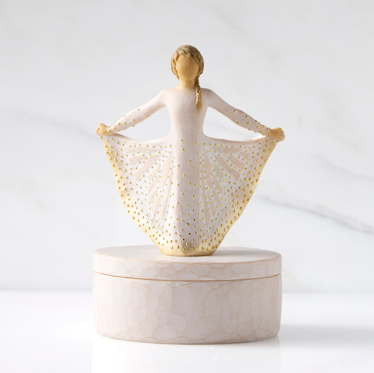 Front view: oval resin box, with 3-D figure in cream and gold carved dress atop lid