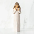 Front view, standing female figure in cream dress, hands surrounding small gold-leaf flame on chest