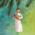 Willow Tree Surprise Ornament 4”h hand-painted resin angel in cream dress, holding large bouquet of purple tulips, brown elastic cord, hanging in front of deep teal painting