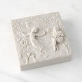 Closed white resin box; lid carved with figural and organic imagery