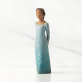 Front/left view: Darker-skin figure, arms clasped behind back, hair and deep blue ombré garment dotted with gold leaf