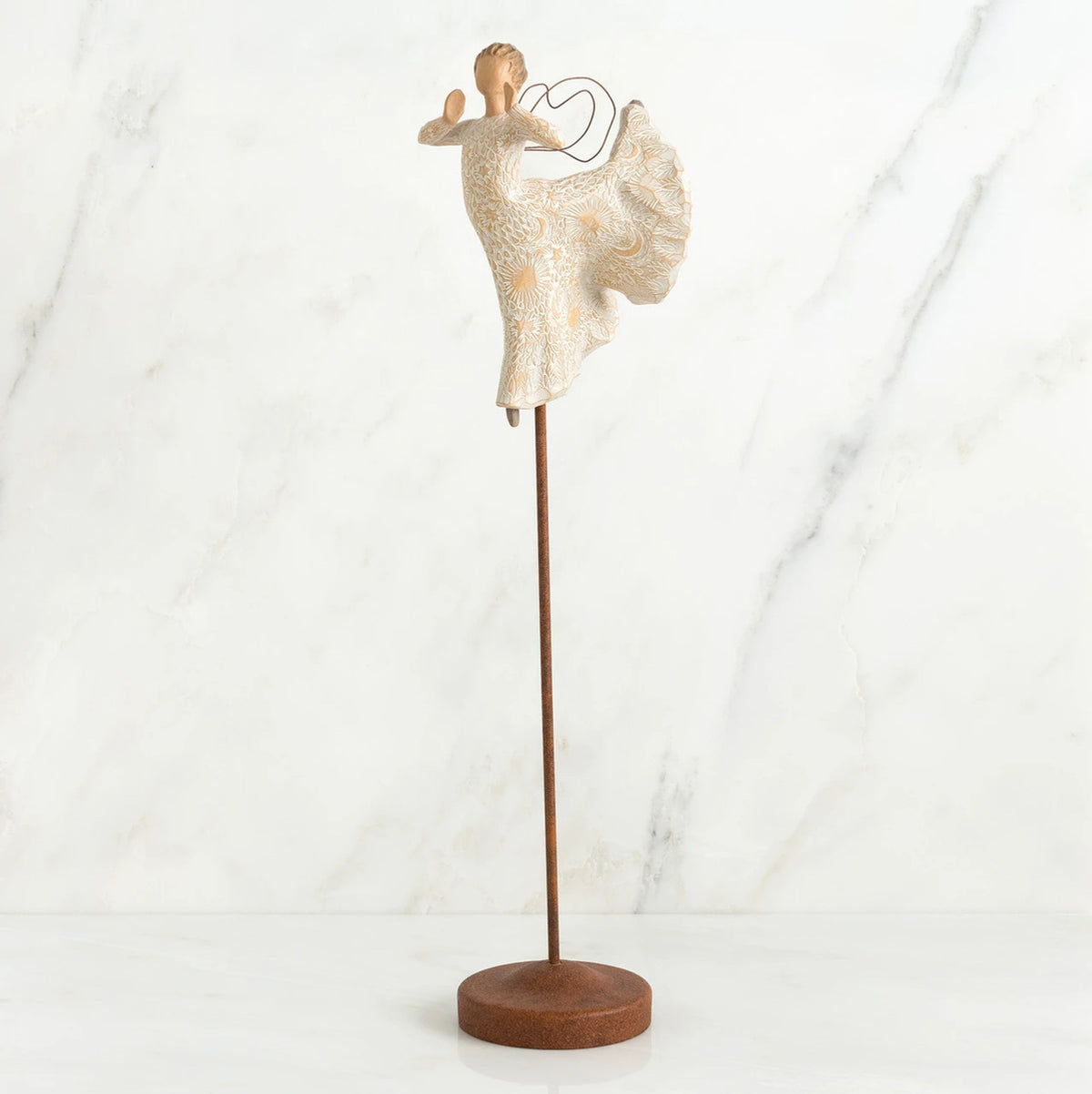 Far shot of angel figurine dressed in white dress dancing with arms and legs out - she is on a brown wooden stand