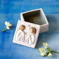 Willow Tree Friendship Keepsake Box, 3”sq x 2”h hand-painted resin box with removable lid off to one side. Lid has bas-relief carving of two seated figures in cream dresses, facing each other, inside of box has sentiment