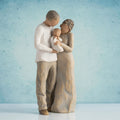 Willow Tree We are Three, 8.5”h hand-painted figure of couple standing together, holding baby between them, all in neutral clothing with darker skin and hair, in front of blue painting