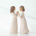 Two brunette girl figurines in white dresses holding hands facing one another