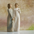 Willow Tree My sister, my friend, 8.5”h hand-painted figure of two females standing next to each other, arms/hands connected, one in cream dress, one in blue/gray dress, in front of dusty pink painting