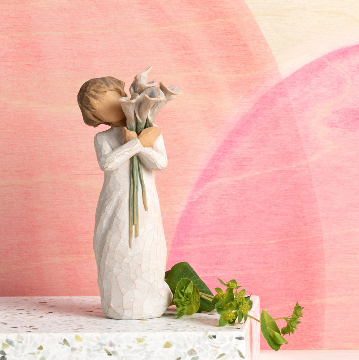 Willow Tree Beautiful Wishes, 5.5”h hand-painted standing resin figure in cream dress, holding bouquet of white calla lilies, in front of pink painting
