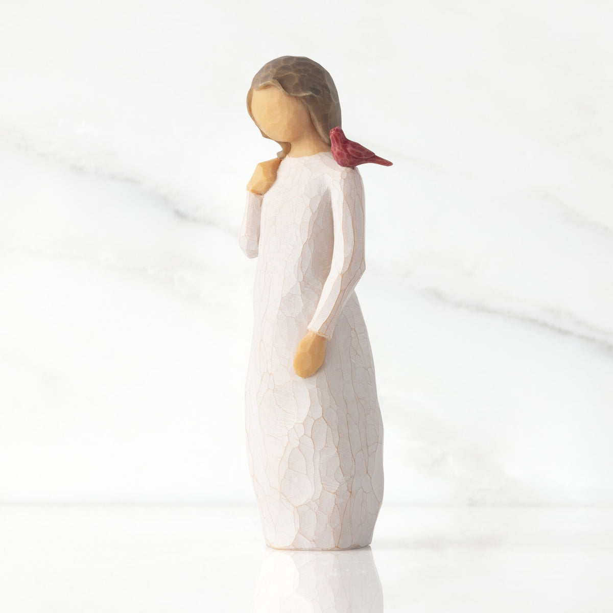 Front view of standing figure in cream dress with cardinal red bird perched on shoulder