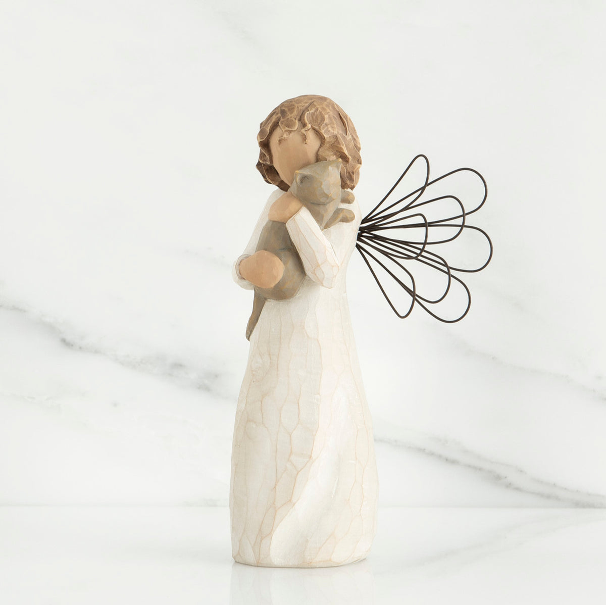 Small brunette angel figurine in white dress holding golden cat