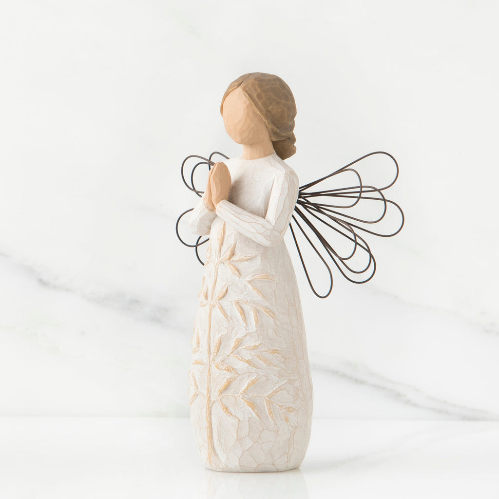 Side view of brunette angel figurine in white dress holding hands in prayer with black wire wings