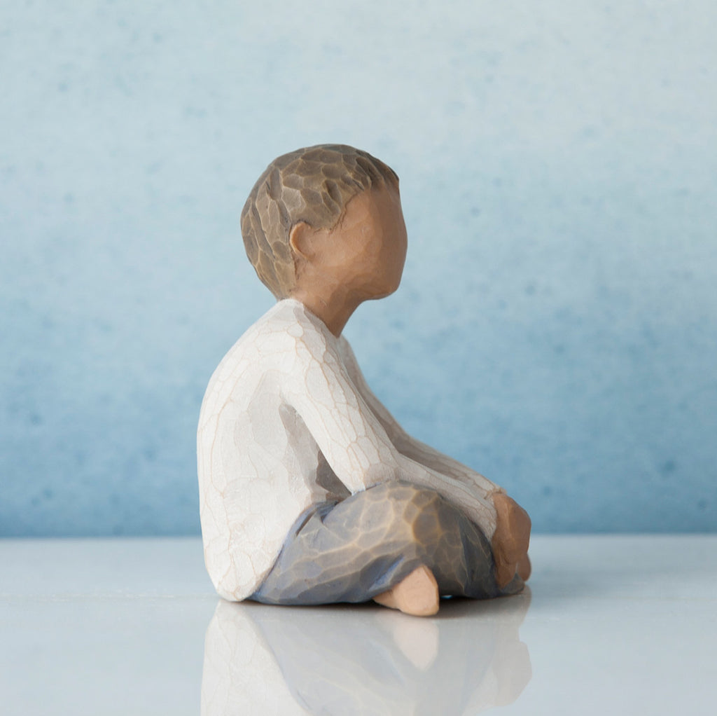 Side view of young boy figurine in white shirt and blue jeans
