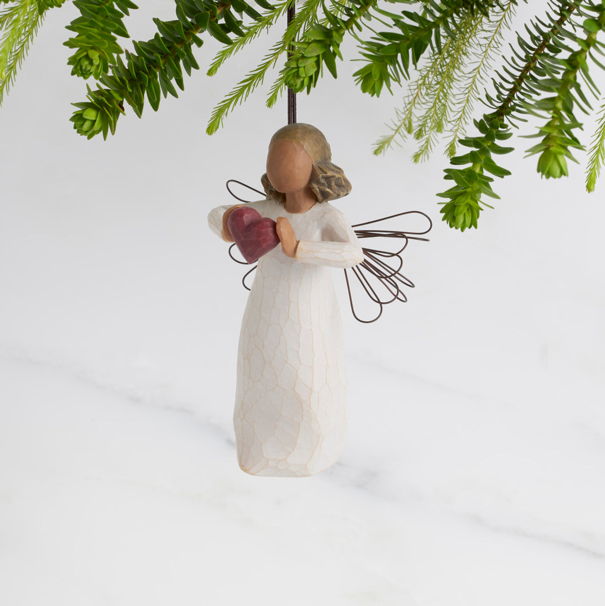 Facing left: Darker-skin Angel with wire wings holding red heart. Loop and hook attached in wings