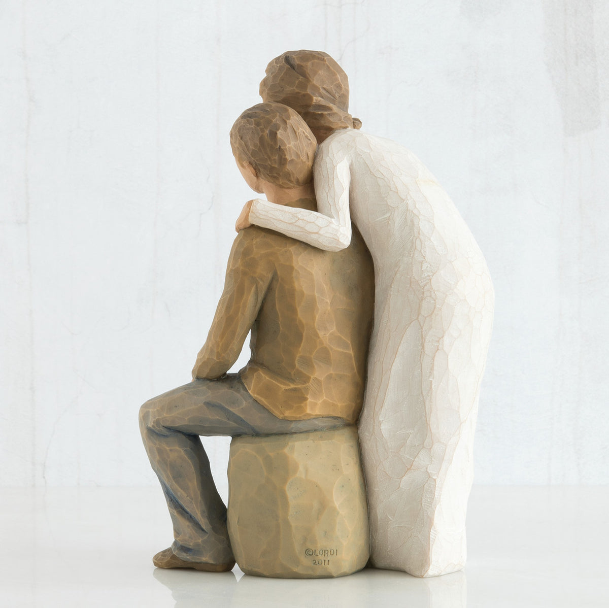 Back view - woman figurine in white dress hugging man figurine in brown shirt and blue jeans