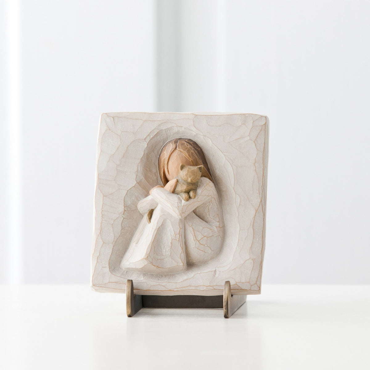 Close view of sqaure pendant with carved in girl figurine centered holding cat figurine