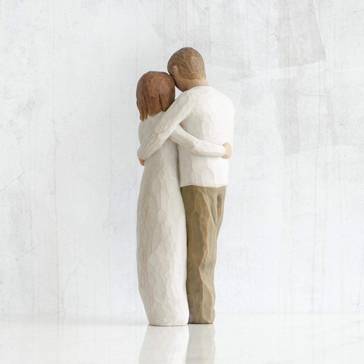 Man and woman figurines - back view - hugging another