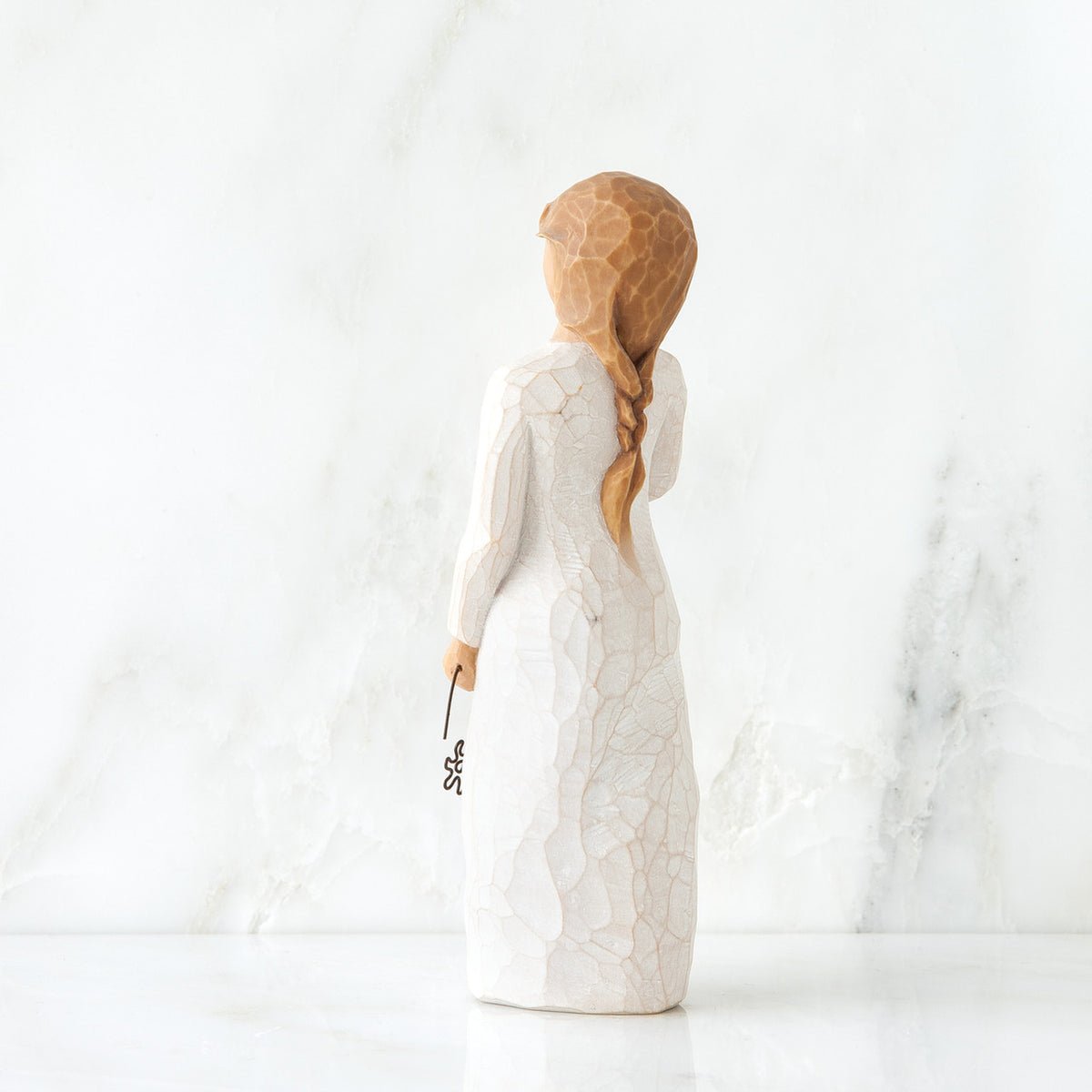 Back view girl figurine in white dress with long red braid