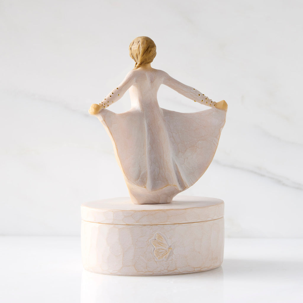 Back view: oval resin box, showing back of 3-D figure in cream dress atop lid