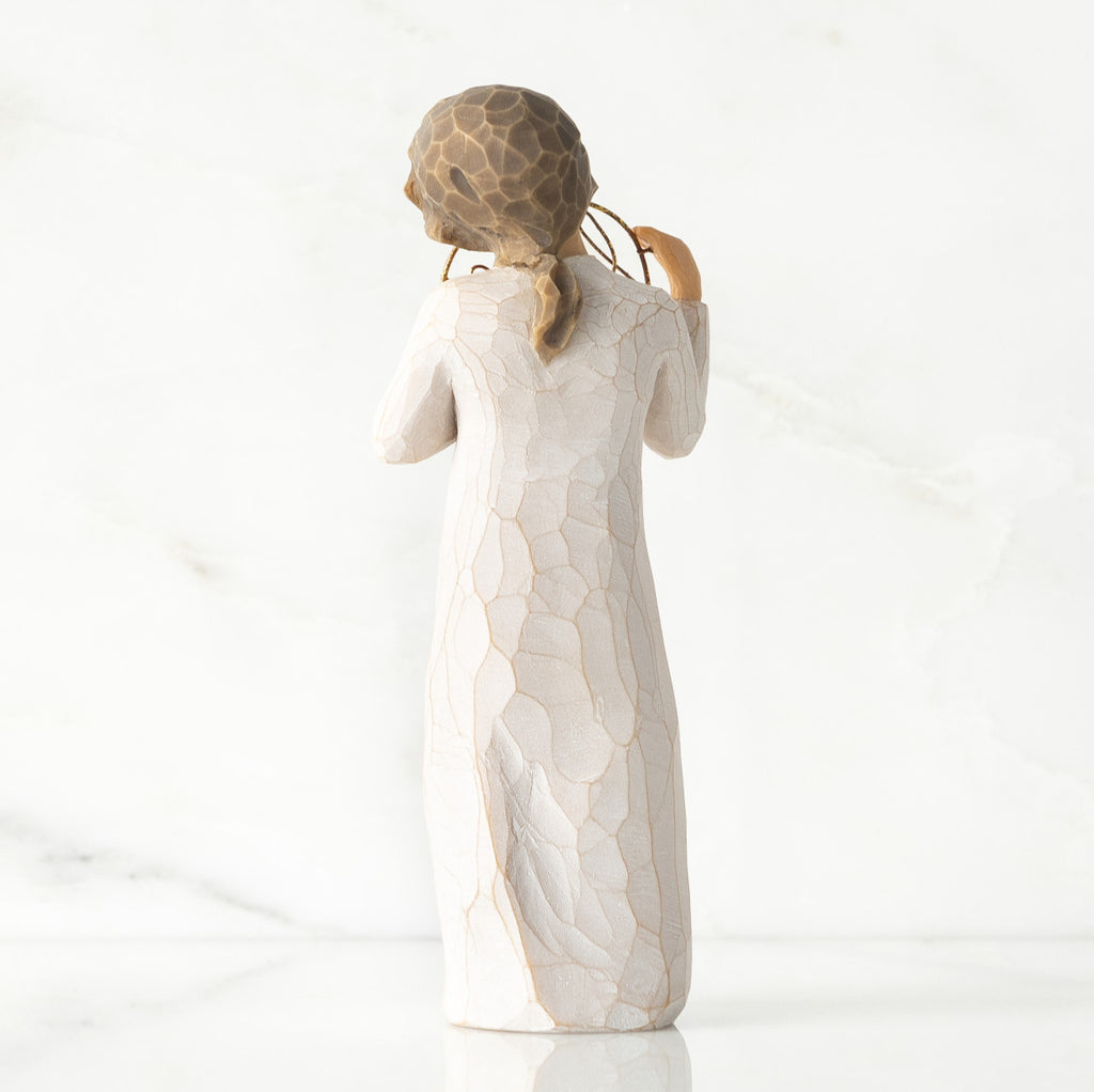 Back view, standing female figure in cream dress, holding gold wire circle in which is written 'love you'