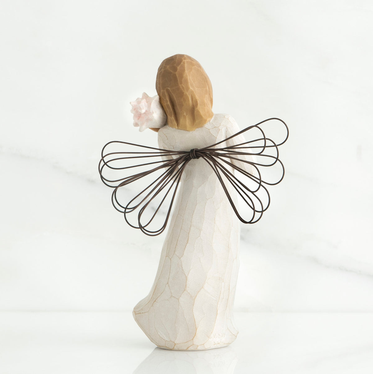 Back view of blonde angel figurine with brown wire wings and white dress
