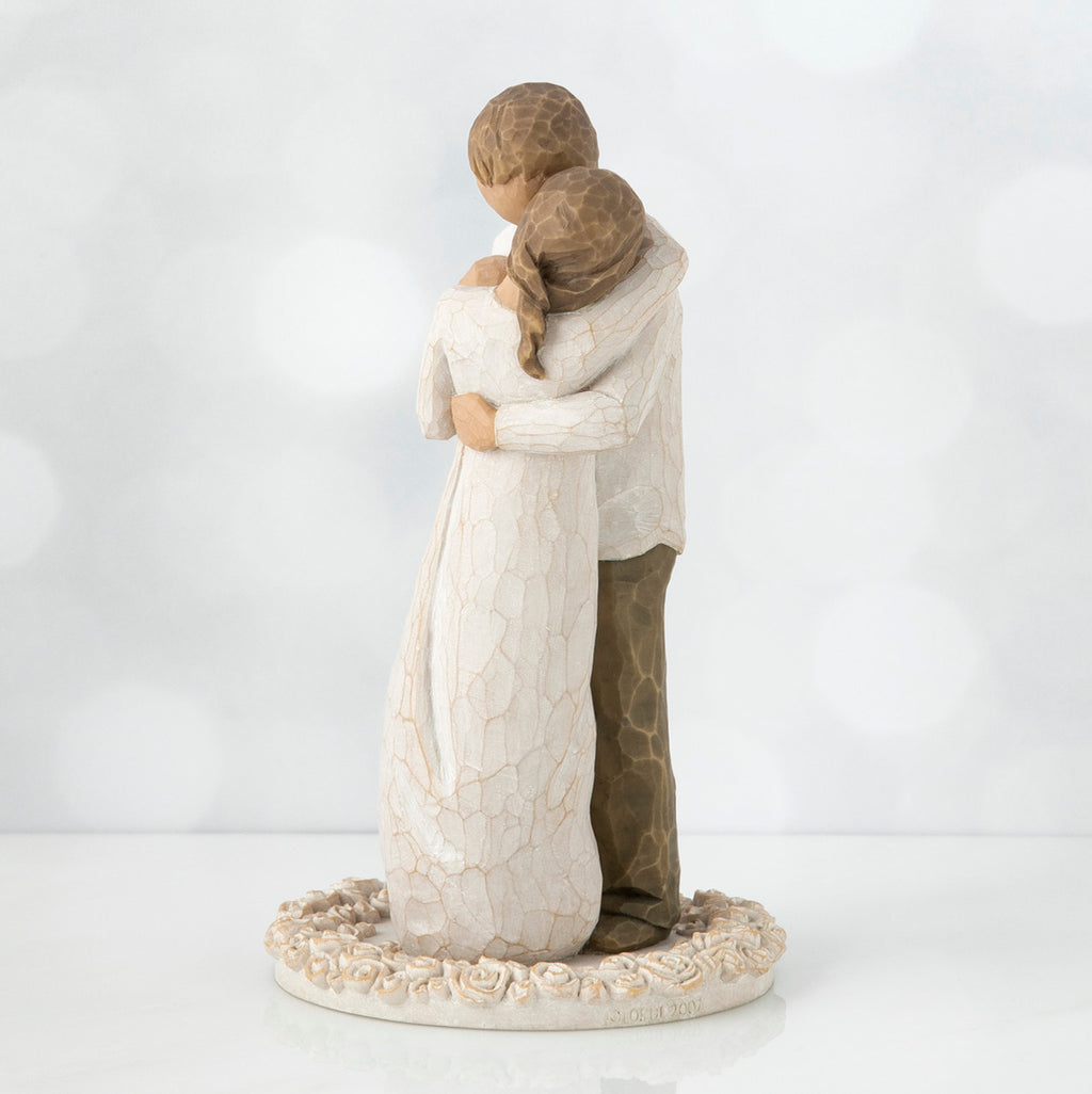 Man and woman figurine hugging one another on round cream plaque