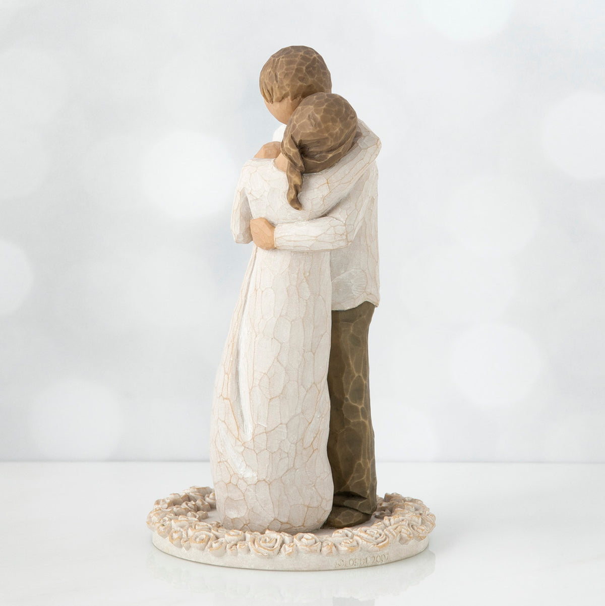 Man and woman figurine hugging one another on round cream plaque