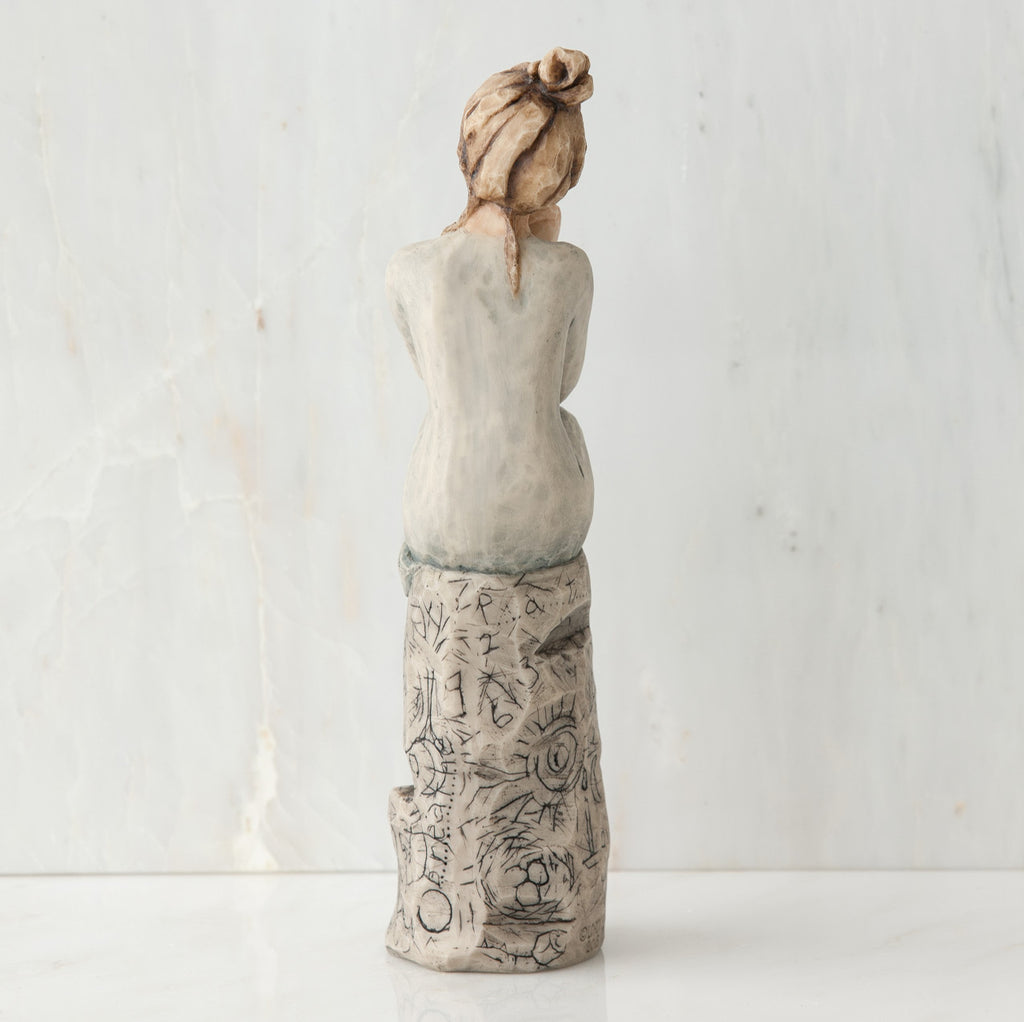 Back view of brunette girl sitting on grey rock