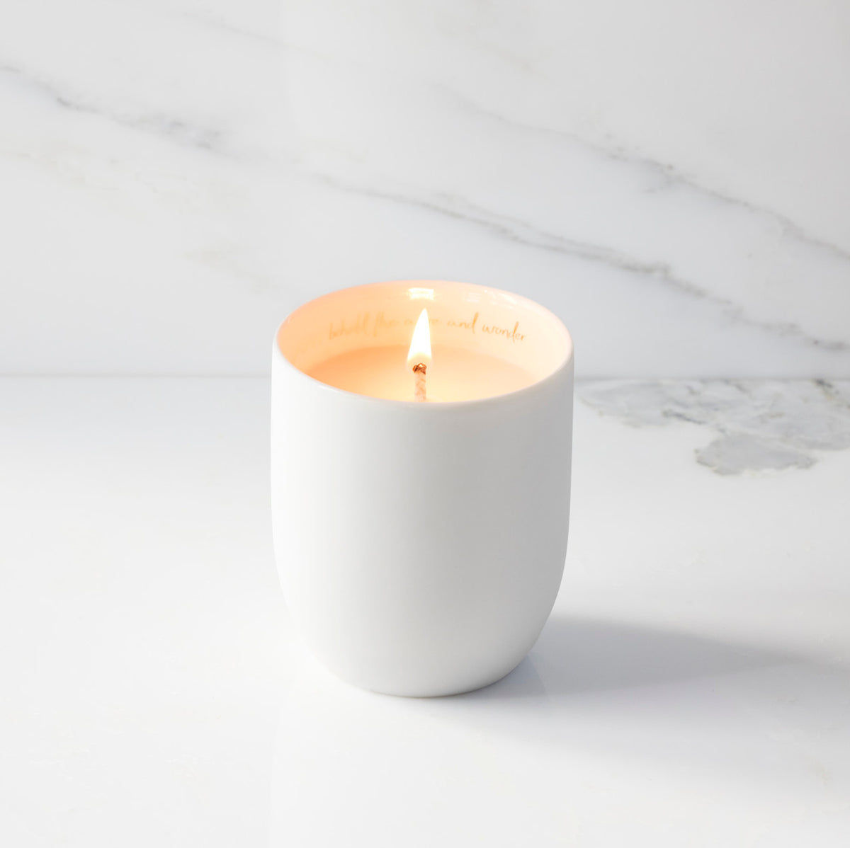 Lit filled scented candle with unglazed cream tapered cylinder vessel, sentiment written in gold inside rim, plant-based wax blend, all-cotton wick