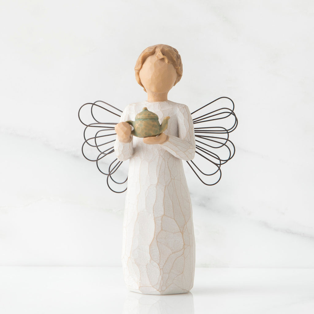 Faceless angel figurine with black wire wings dressed in white holding teapot