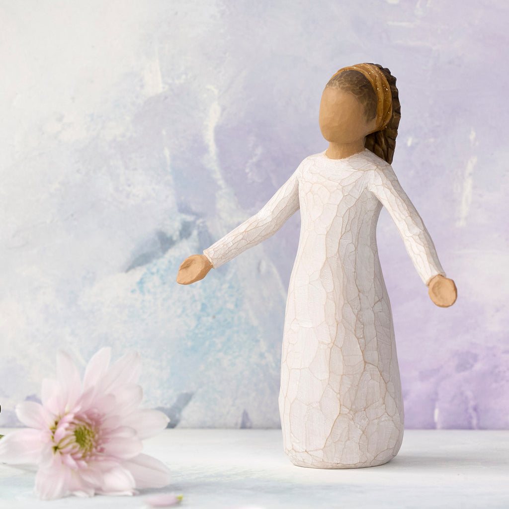 Willow Tree Blessings, 5.5”h hand-painted resin figure in cream dress with darker skin and hair, wearing glitter headband, arms stretched out to sides, in front of light purple painting