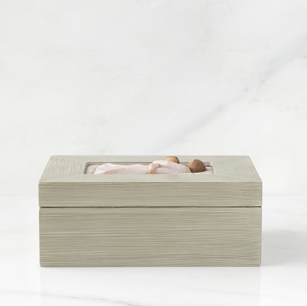 Side view: Light gray rectangular wood box with hinged lid, carving on lid of female and child embracing in cream dresses