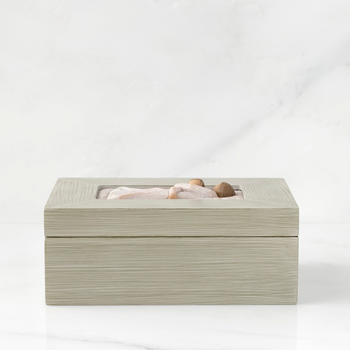 Side view: Light gray rectangular wood box with hinged lid, carving on lid of female and child embracing in cream dresses