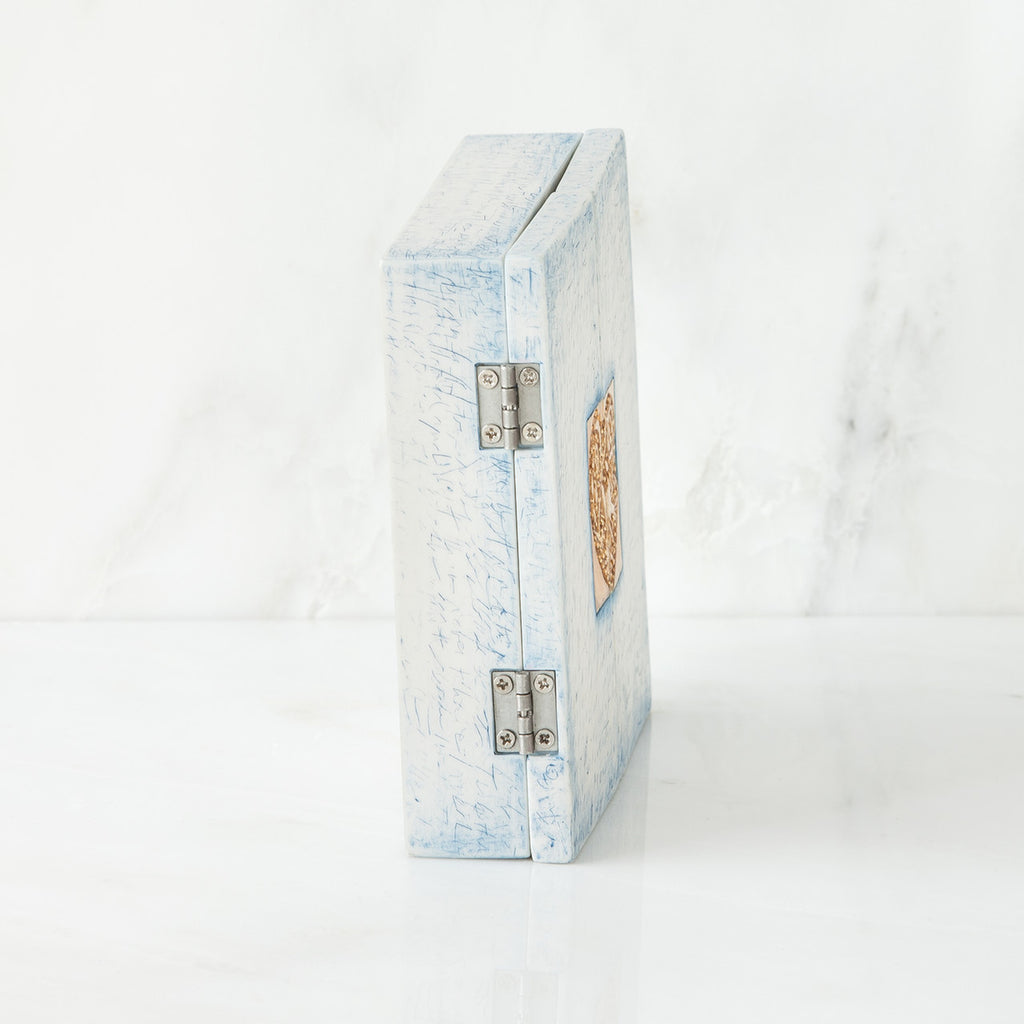 Side view of light blue/white wooden book standing up white background