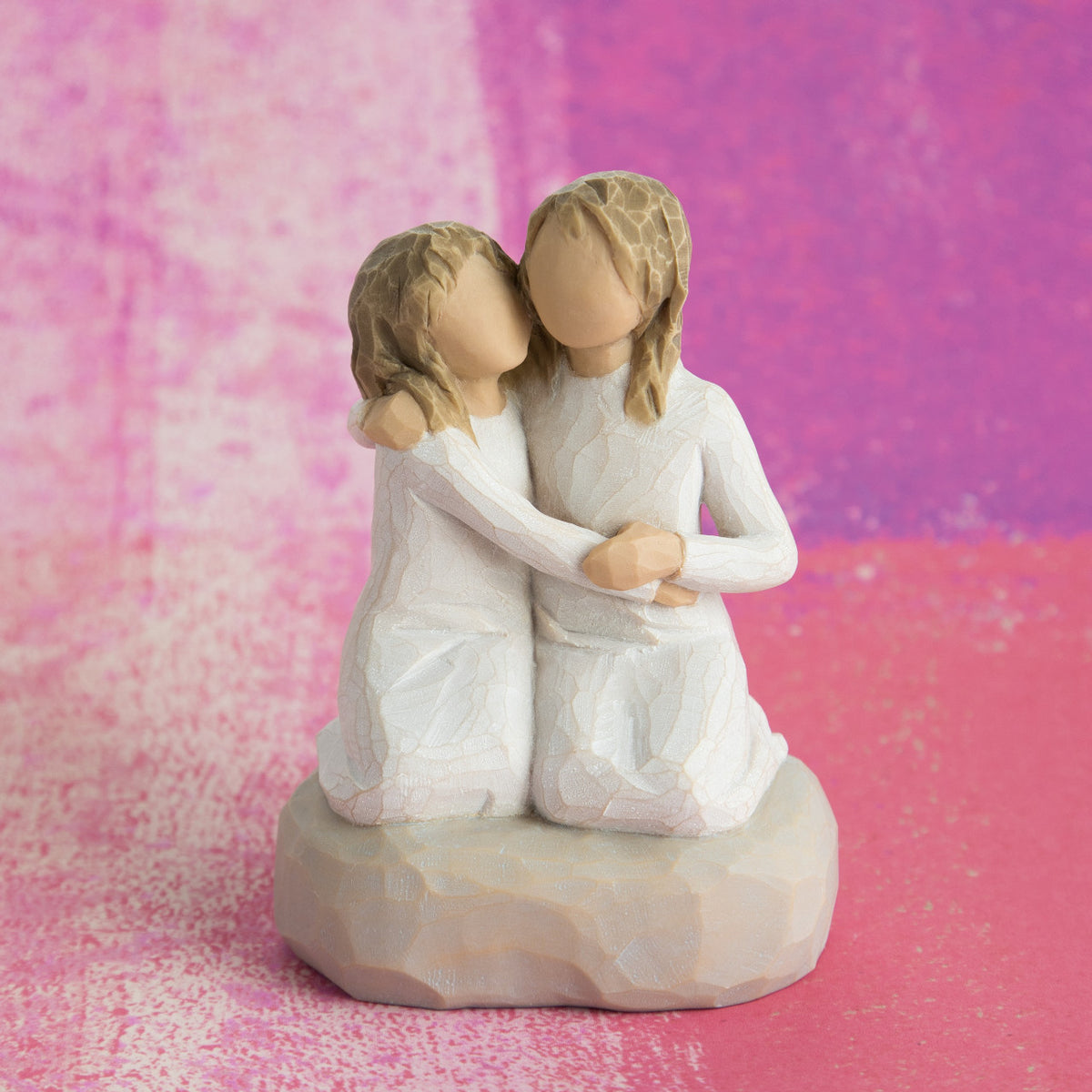 Willow Tree Sister mine, 4”h hand-painted resin figure of two girls in cream dresses, kneeling with arms around each other, in front of vibrant pink painting