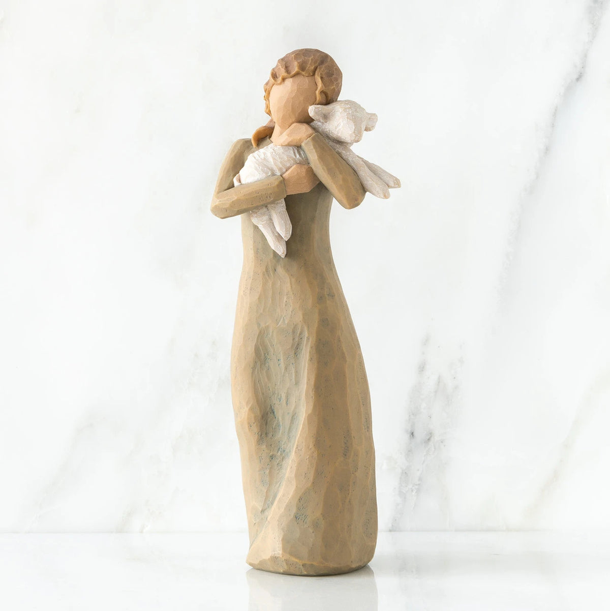 Faceless woman figurine standing wearing light tan dress holding white lamb in her arms