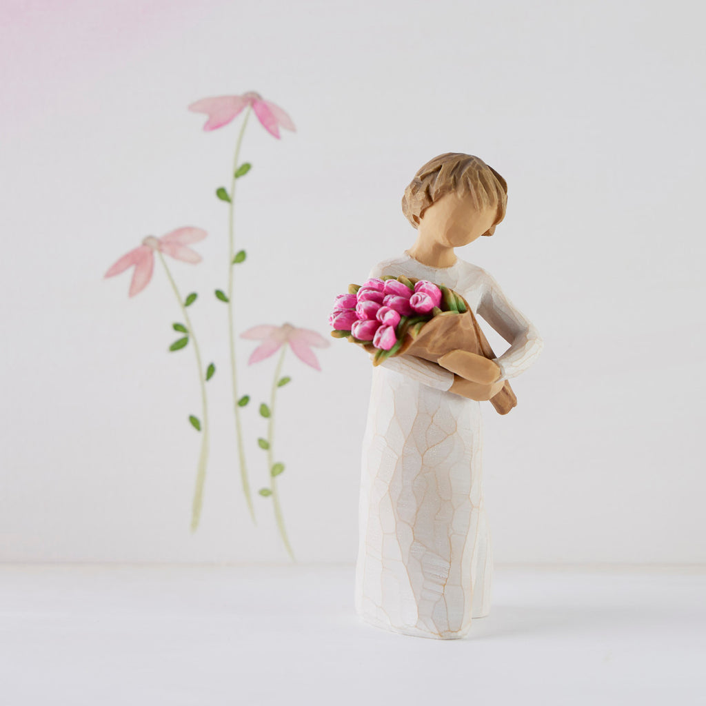 Willow Tree Bright Hope, 4”h hand-painted standing figure in cream dress, holding bouquet of bright pink tulips, in front of white painting