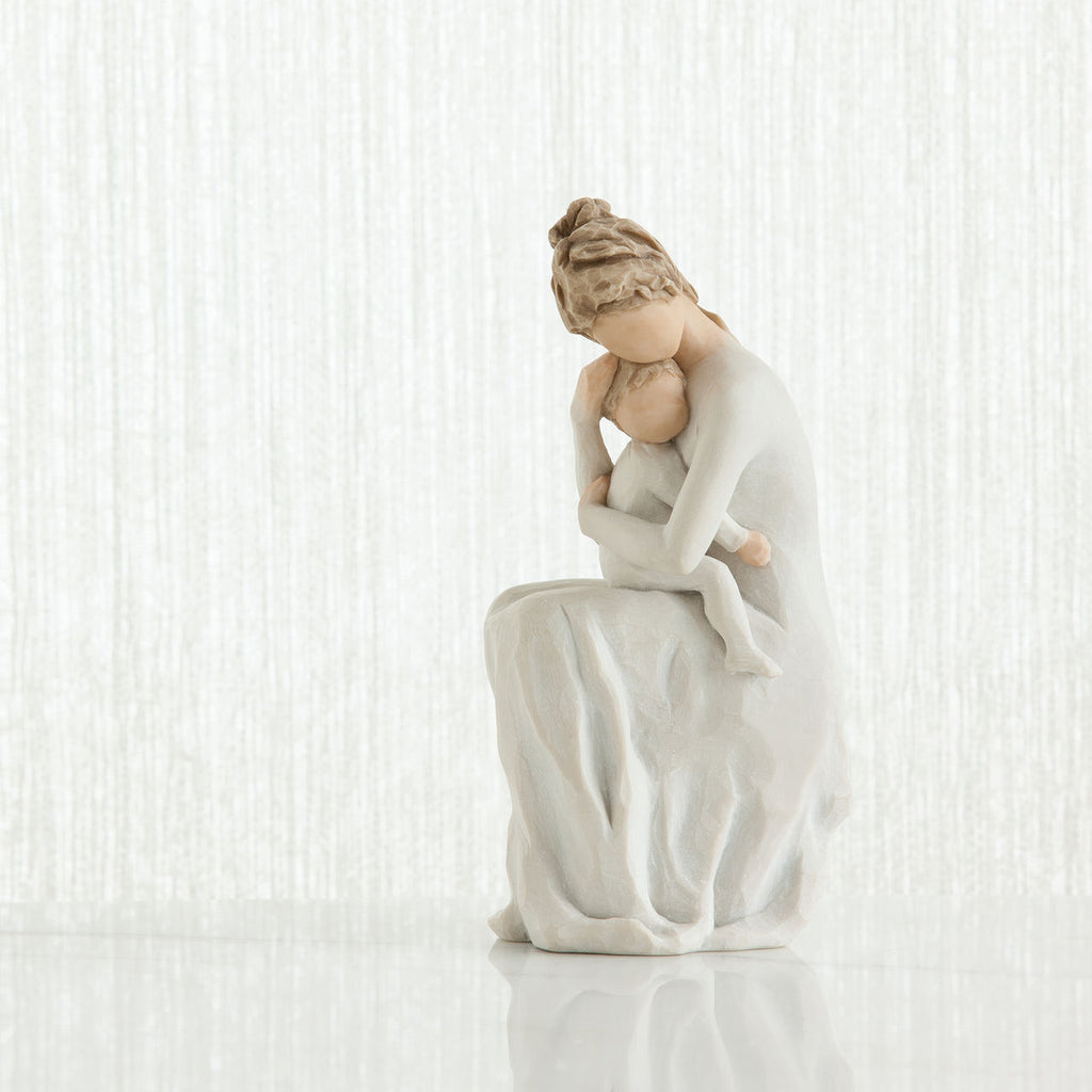 Faceless mother figurine sitting down holding baby - all wearing white and all white background
