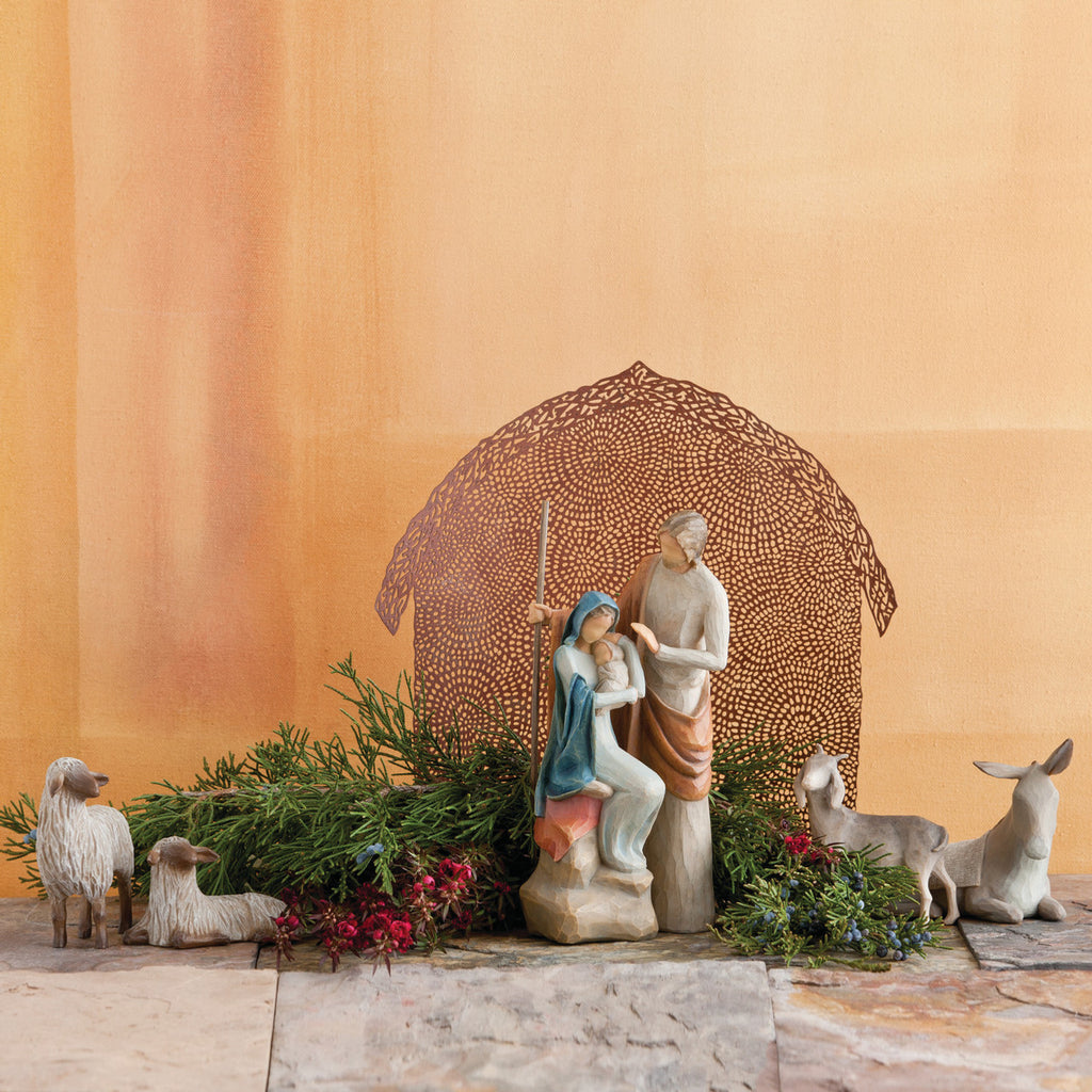 Far view of nativity scene figurines sitting on rock with brown barn in the background