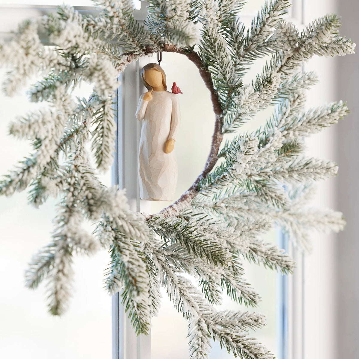 Willow Tree Messenger Ornament, 4”h hand-painted resin figure in cream dress with red cardinal on shoulder, brown elastic cord, hanging inside winter wreath
